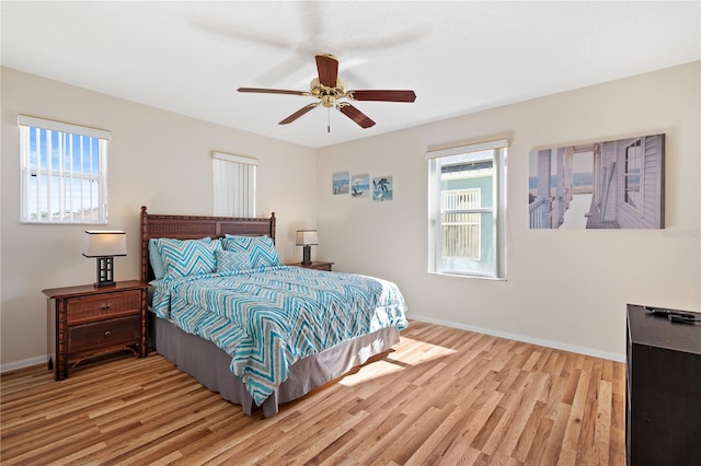 bedroom with multiple windows, wood finished floors, and baseboards