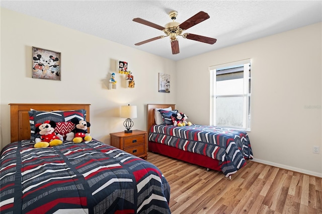 bedroom featuring ceiling fan, baseboards, a textured ceiling, and wood finished floors