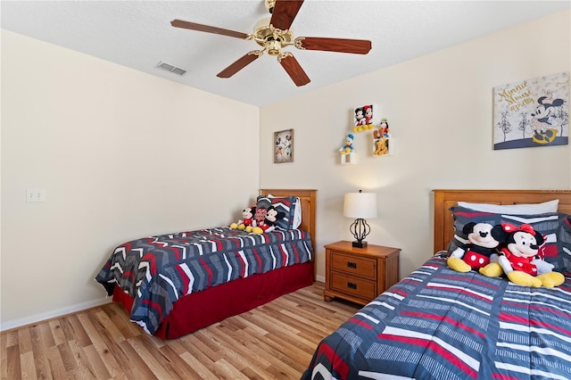 bedroom featuring visible vents, baseboards, ceiling fan, and wood finished floors