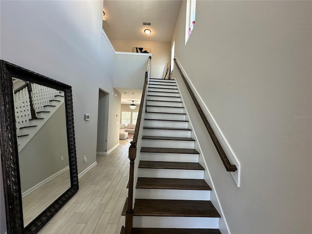 staircase featuring visible vents, baseboards, a high ceiling, and wood tiled floor