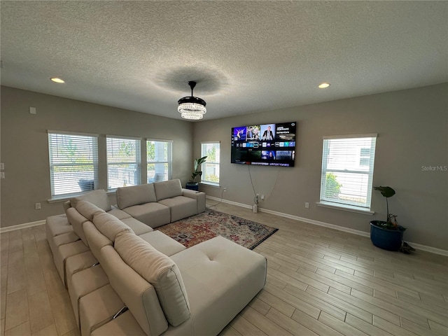 living room featuring light wood-type flooring, baseboards, and a healthy amount of sunlight