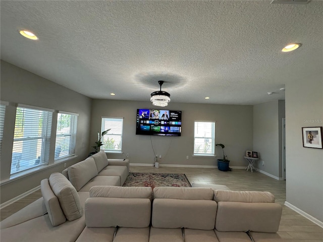 living room featuring recessed lighting, a textured ceiling, baseboards, and wood finished floors