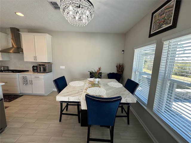 dining room with visible vents, baseboards, a notable chandelier, and a textured ceiling