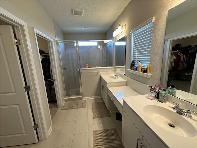 bathroom with visible vents, a stall shower, a textured ceiling, and vanity