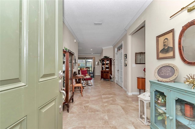 hallway featuring light tile patterned floors, a textured ceiling, baseboards, and ornamental molding