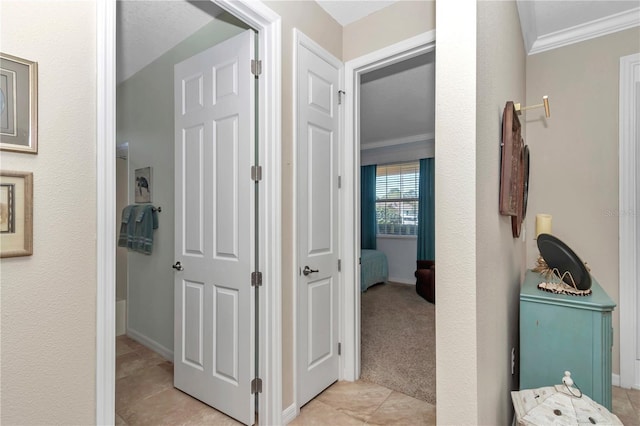 corridor with light tile patterned flooring, light carpet, crown molding, and baseboards