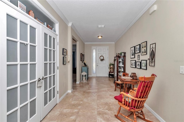 foyer with a textured ceiling, crown molding, and baseboards