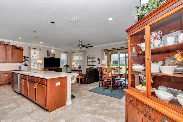 kitchen with open floor plan, dishwasher, light countertops, brown cabinets, and a sink