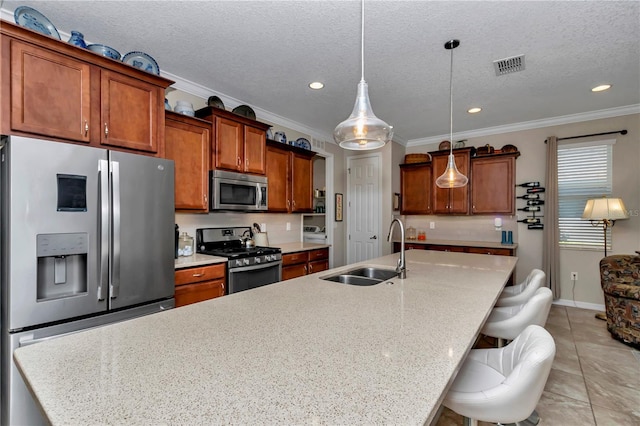 kitchen with visible vents, brown cabinets, a sink, a spacious island, and stainless steel appliances