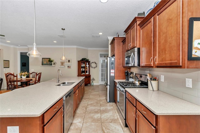 kitchen with backsplash, an island with sink, brown cabinets, stainless steel appliances, and a sink