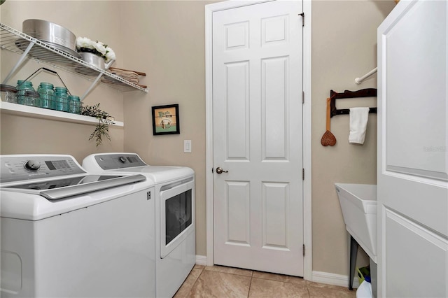 laundry room featuring laundry area, light tile patterned floors, separate washer and dryer, and baseboards