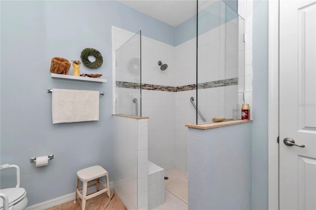 bathroom with toilet, a walk in shower, and baseboards