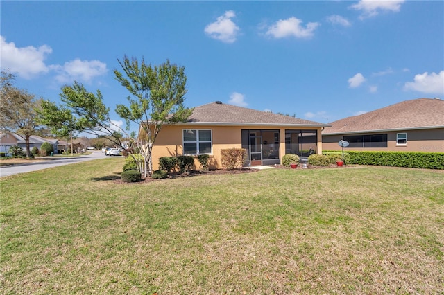 back of property with a yard, a sunroom, and stucco siding