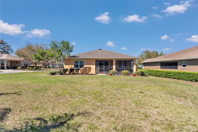 back of property featuring stucco siding, a yard, and a sunroom