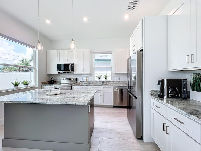 kitchen with stainless steel appliances, light stone countertops, visible vents, and decorative backsplash