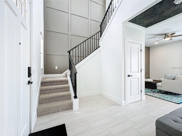 stairs featuring baseboards and a ceiling fan