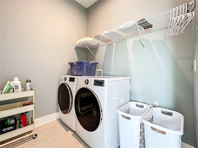 laundry room with washer and dryer, baseboards, wood finished floors, and laundry area