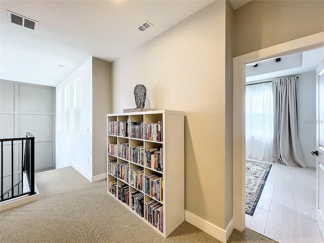 hall with visible vents, baseboards, and carpet