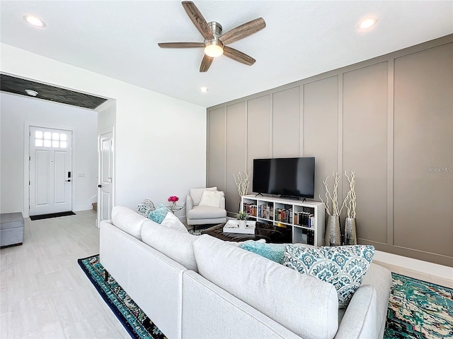 living area with a decorative wall, recessed lighting, and a ceiling fan