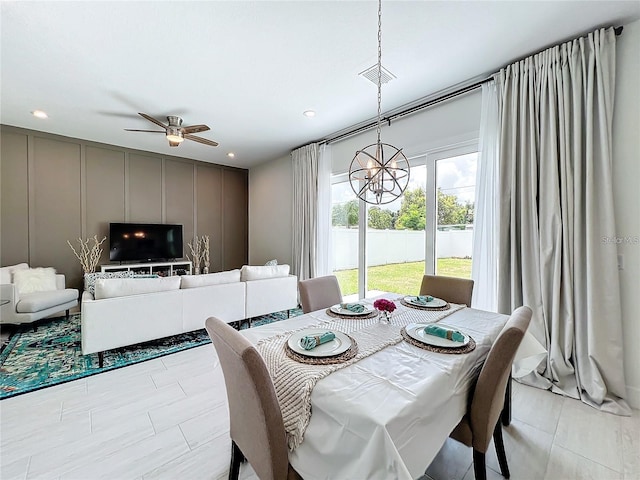 dining space with recessed lighting, a decorative wall, ceiling fan with notable chandelier, and visible vents