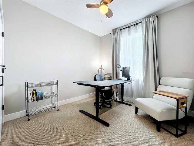 carpeted home office with a textured ceiling, baseboards, and a ceiling fan