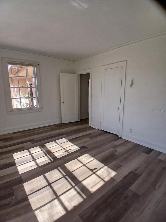 unfurnished room featuring baseboards and dark wood finished floors