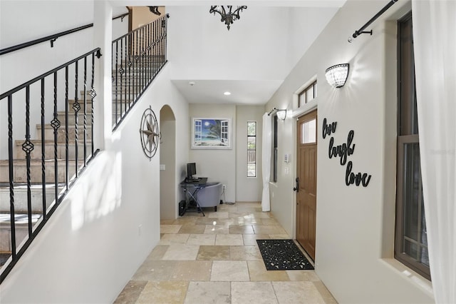 foyer entrance with stone tile flooring, stairway, recessed lighting, and a high ceiling