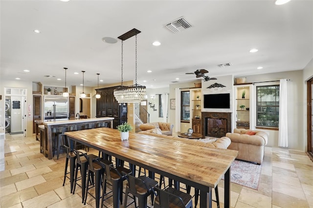 dining space with stone tile flooring, visible vents, a glass covered fireplace, and stairway