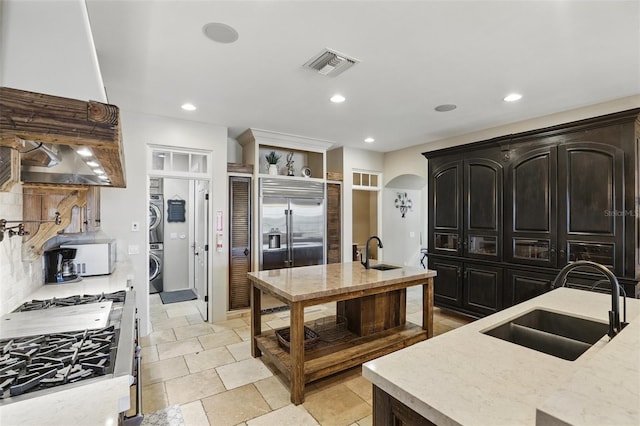 kitchen featuring a sink, visible vents, stacked washer and dryer, and backsplash