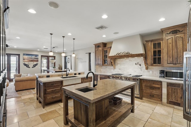 kitchen featuring visible vents, an island with sink, a sink, custom range hood, and premium appliances