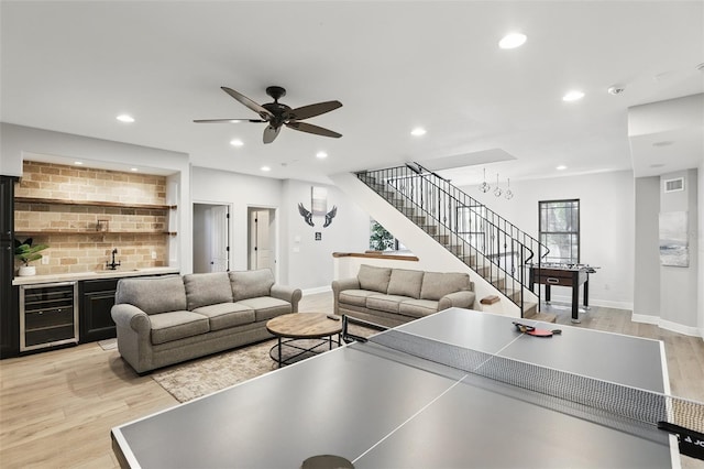 living area featuring stairway, beverage cooler, light wood finished floors, wet bar, and recessed lighting