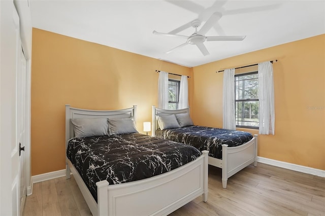 bedroom with ceiling fan, light wood-type flooring, and baseboards