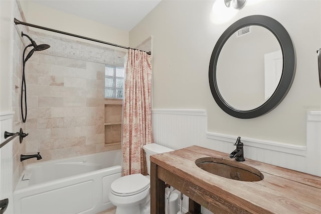 bathroom featuring visible vents, a wainscoted wall, a sink, toilet, and shower / tub combo with curtain