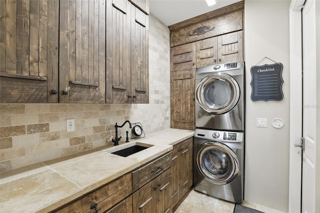 clothes washing area featuring a sink, cabinet space, and stacked washer / dryer