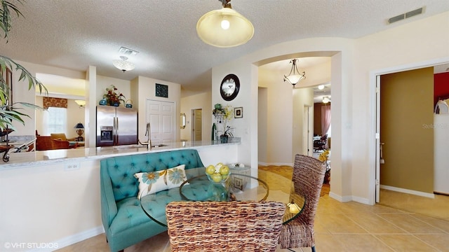 tiled dining area featuring a textured ceiling, arched walkways, visible vents, and a sink