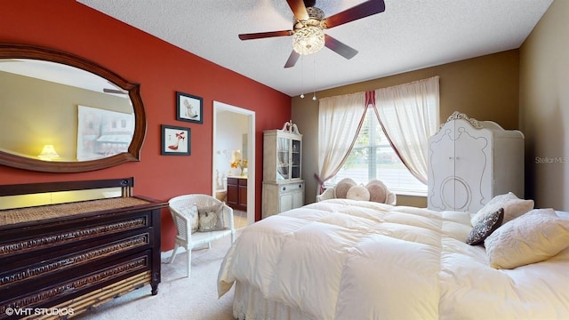 bedroom featuring ensuite bath, carpet flooring, a ceiling fan, and a textured ceiling