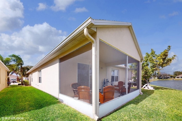 exterior space with stucco siding, a lawn, and a sunroom