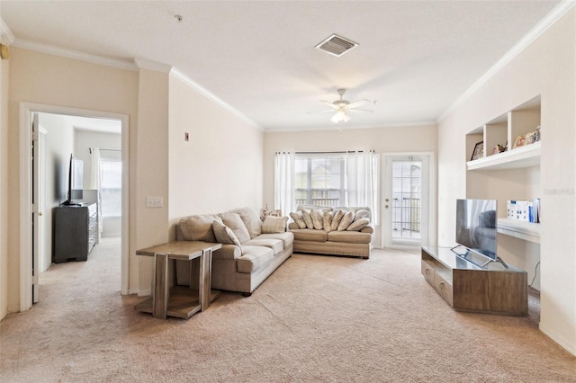 carpeted living area with visible vents, crown molding, and a ceiling fan