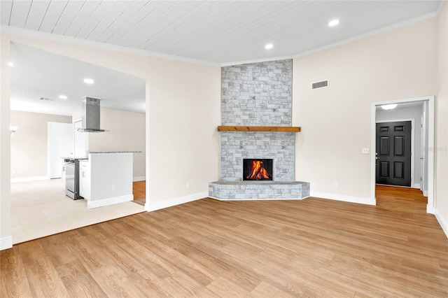 unfurnished living room with baseboards, visible vents, light wood-style flooring, a fireplace, and ornamental molding