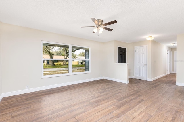 unfurnished room featuring ceiling fan, wood finished floors, baseboards, and a textured ceiling