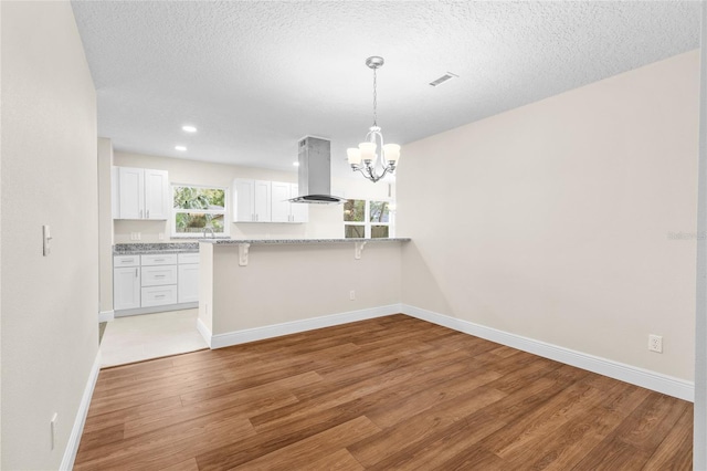 unfurnished dining area featuring light wood-style flooring, plenty of natural light, baseboards, and visible vents