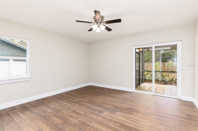 unfurnished room featuring baseboards, a textured ceiling, wood finished floors, and a ceiling fan