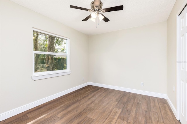 spare room featuring dark wood finished floors, a ceiling fan, and baseboards