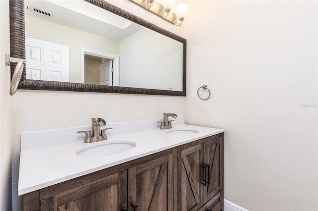 bathroom with double vanity, visible vents, and a sink