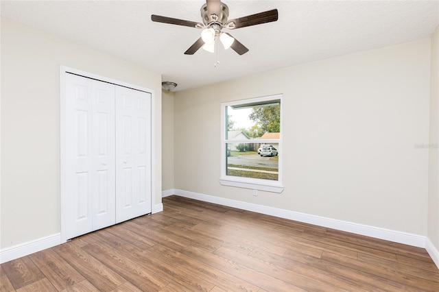 unfurnished bedroom with ceiling fan, a closet, baseboards, and wood finished floors