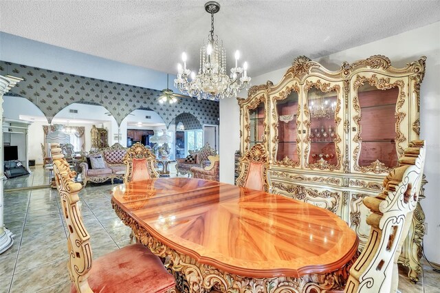 tiled dining area with a textured ceiling, arched walkways, and a chandelier