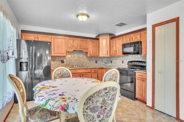 kitchen featuring black appliances, tasteful backsplash, visible vents, and a sink