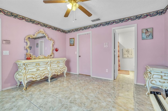 sitting room with a textured ceiling, light tile patterned floors, visible vents, and ceiling fan