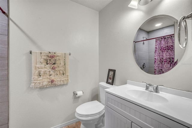 bathroom with vanity, toilet, baseboards, and tiled shower