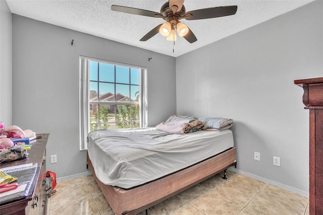 bedroom with light tile patterned flooring, a textured ceiling, baseboards, and a ceiling fan